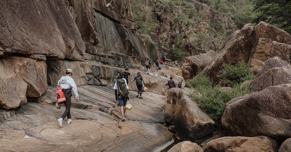 A group of hikers explores a rugged landscape with large boulders and natural vegetation.