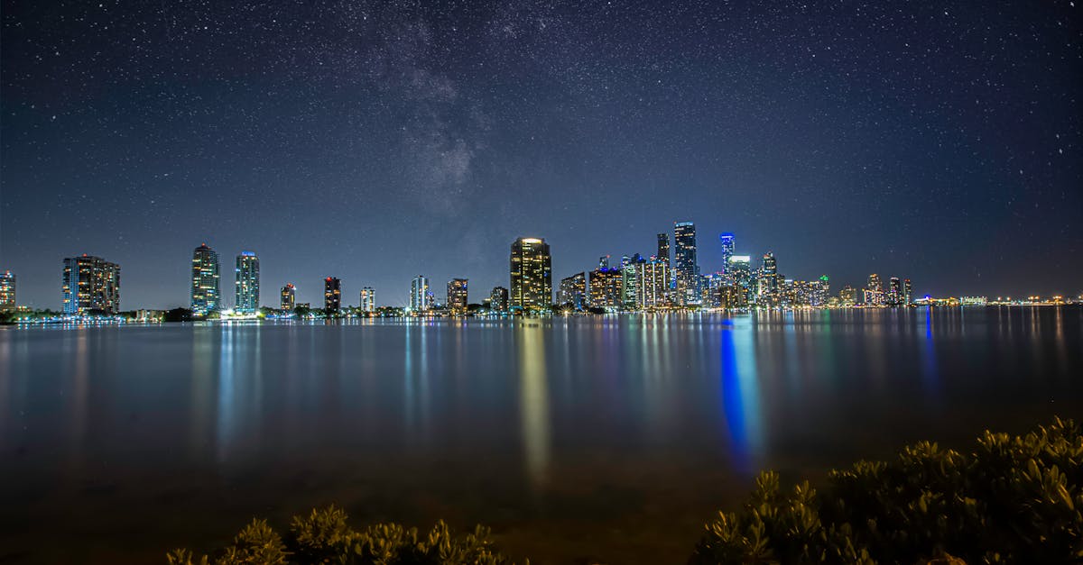 Breathtaking view of Miami's skyline at night with a star-filled sky reflecting over the water.