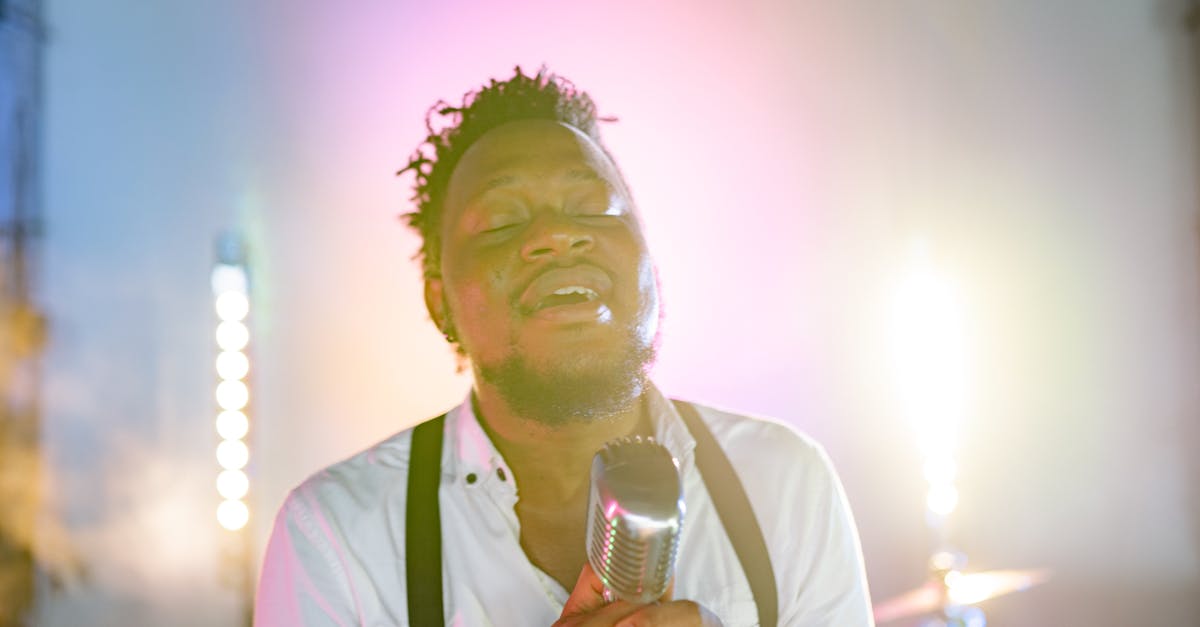 An African American man passionately singing into a retro microphone on stage.