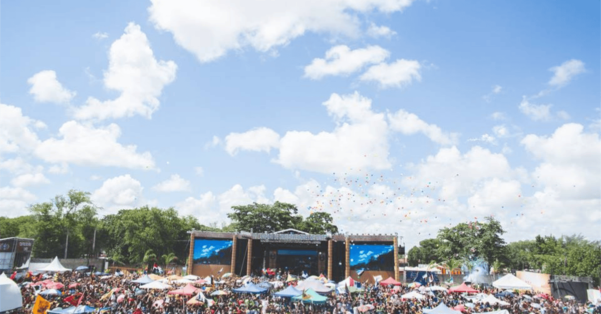 Lively outdoor festival with large crowd, vibrant umbrellas, and a clear sky in Santos Reis, Brazil.