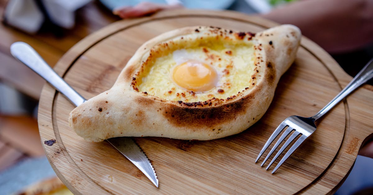 Savor the traditional Georgian khachapuri with an egg, served on a wooden plate, offering a taste of authentic Tbilisi cuisine.