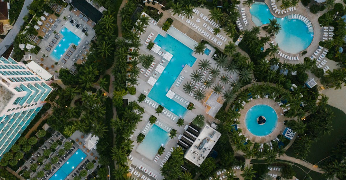 Aerial view of a luxury resort featuring swimming pools, palm trees, and elegant architecture at a tropical destination.