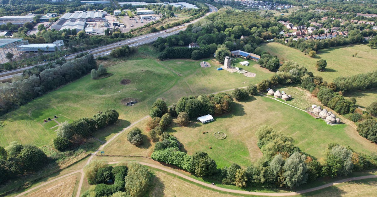 Aerial shot of green countryside landscape in Milton Keynes, England, featuring fields, trees, and rural buildings.
