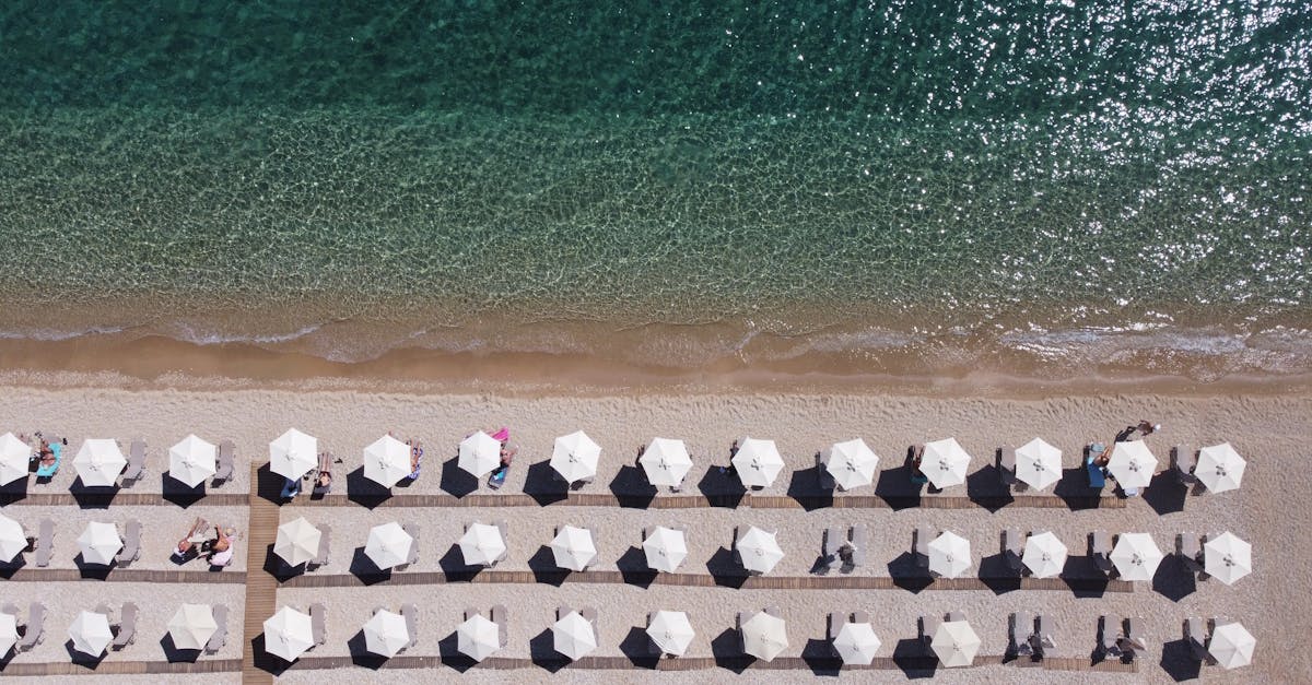 Aerial image of Mparmpati Beach, Greece, featuring rows of sun umbrellas by the clear blue sea.